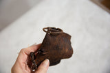 Time-softened, rustic iron texture of a hand-held vintage African cow bell.