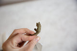 Side view of the small pangolin pendant showing its handmade texture and oxidized bronze finish.