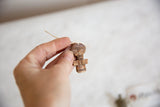 Hand holding a carved vintage African wooden person pendant with natural string.