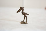 Side profile of a vintage African dark bronze stork with incised textural details.