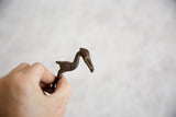 Side profile of a vintage bronze stork figure showing its textured, handmade details.