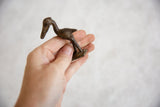 Small vintage bronze stork sculpture held in hand to demonstrate its scale.