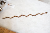 Slithering form of the vintage African iron snake, showing its rusty patina.