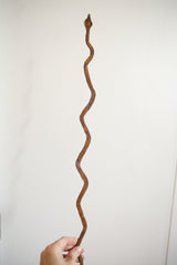 Hand holding the rusty, textured vintage African iron snake sculpture.