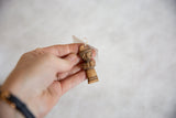 Vintage carved wooden pendant held to show its small scale and handmade details.