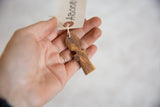 Vintage African wooden person pendant held in hand to show its scale and texture.