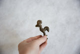 Small vintage African bronze rooster held to show its scale and handmade texture.