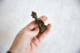Small vintage African bronze rooster figurine held in hand to show scale.