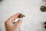 Vintage African bronze turtle pendant held in hand to demonstrate its small scale.
