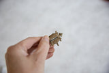 A small African bronze turtle pendant with mesh texture held in hand for scale.