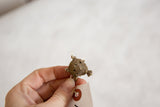 A hand holds the vintage bronze turtle pendant, showing its scale and coiled wire shell.