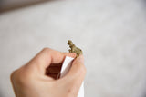 Small bronze turtle pendant held in hand to show its scale and coiled wire shell.