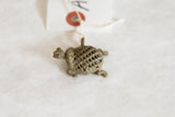 Handmade details of the vintage bronze turtle pendant's criss-cross mesh shell.