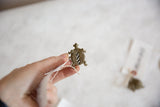 Vintage African bronze turtle pendant held in hand, showing its scale and textured finish.