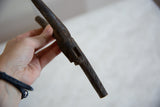 Dark brown vintage African wooden talisman held in hand, showing unique carved texture.