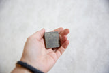 Vintage African square bronze coin, displaying its uniquely textured, patinated surface.