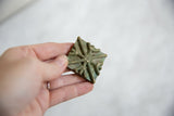 Vintage African bronze coin held to show its handmade texture and scale.