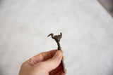 Vintage African bronze bird pin held in hand to demonstrate its scale and form.