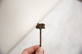 The slender, handmade form of a vintage African bronze chameleon pin held in hand.