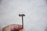 Aged patina and handmade texture on the head of a vintage bronze chameleon pin.