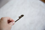 Side view detailing the scrolled tail and textured head of the bronze chameleon pin.