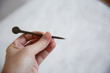 Vintage African bronze pin held to demonstrate its slender form and full length.