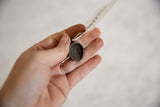 The hollow, textured reverse side of the small dark bronze African mask pendant.
