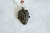 Close-up of handmade vintage African bronze mask pendant with rich patina.