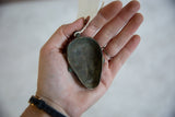 Concave back of vintage African bronze mask pendant, revealing green patina.