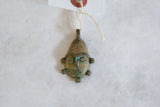 Aged bronze texture and green patina on a vintage African mask pendant.