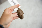 Hand-held view of the large African bronze mask pendant showing its scale and texture.