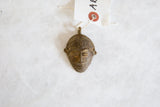 Handmade African bronze mask pendant with a weathered patina and inventory tag.