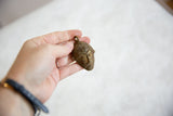 Vintage African bronze mask pendant held to show scale and handmade patina.