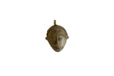 Vintage African bronze mask pendant with a stylized face and textured handmade details.