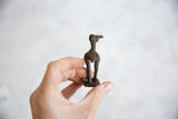Vintage African dark bronze stork sculpture, held in hand, showing its textured back and legs.
