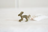 Vintage bronze hare pendant's animated posture and handmade texture seen in profile.