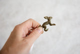 Vintage African bronze hare pendant held to show its petite size and handmade form.