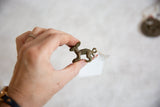 Hand holding the small oxidized bronze hare pendant to illustrate its size.