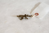 Vintage African bronze crocodile pendant with its white paper tag attached by a string.