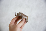 Small vintage bronze rhino with an aged patina held in hand for scale.