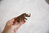 Vintage African copper alloy rhino held by hand, showcasing its aged patinated finish.