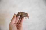 Hand holds vintage African thin-nosed rhino, revealing copper alloy and patina.