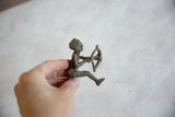 Hand holding the vintage African aluminum archer, highlighting its handmade texture.