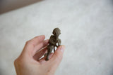 Hand-held close-up of the vintage African aluminum archer, showing rough textured detail.