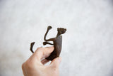 Hand holding the vintage African bronze man to show its scale and handmade form.
