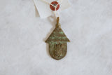 Vintage African bronze hut pendant with a green oxidized patina and a central bug motif.