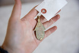 The flat reverse of the vintage bronze hut pendant showing its aged, oxidized patina.