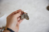 The unique cast texture of a vintage African bronze pendant held in a person's hand.