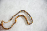 Handmade African flour beads, showing muted blue, red, yellow stripes and straw string.