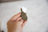 Vintage African bronze spotted hut pendant in a hand, highlighting its handmade texture.